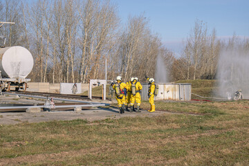 A group of rescuers equipped with breathing apparatus at the scene of an accident at a petrochemical plant. Elimination of an accident at a petrochemical plant. There is an emergency at the factory.