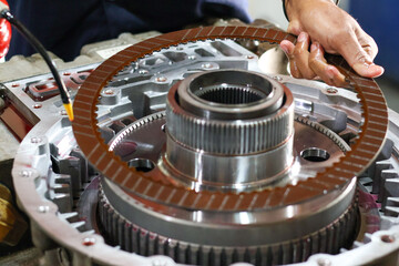 ​A mechanic's hand carefully places a clutch friction plate into a complex transmission assembly...
