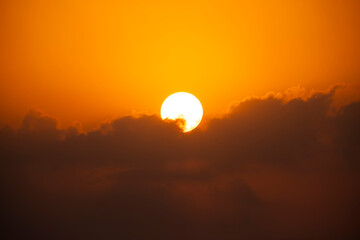 Sunrise emerging through clouds at dawn. Golden sun rising among morning clouds. Scenic sunrise with cloudscape. Dramatic sunrise sky with clouds.