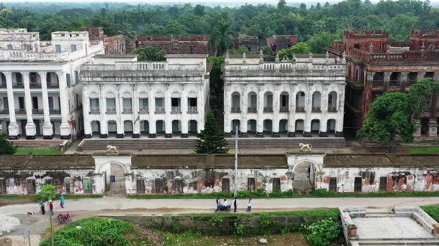 Manikganj, Bangladesh - 22 August 2025: Aerial view of Baliati Zamindar Bari's aged white buildings contrasting with the lush green trees surrounding the historical site.