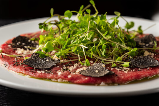 Beef carpaccio with black truffle shavings, fresh microgreens, and sea salt flakes on a white plate. Elegant fine dining presentation. Ideal for gourmet and upscale restaurant menus