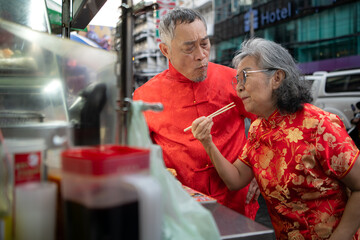 A happy senior couple strolls along a Chinatown in Bangkok, Thailand,