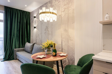 cozy dining area features a round table set with champagne, flowers, and star dishes, illuminated...