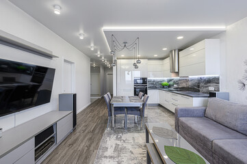 modern, bright living space featuring a kitchen, dining area, and living room. The decor is...