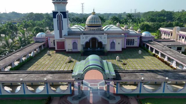 Barishal, Bangladesh - 22 August 2025: Aerial view of the Baitul Aman Jame Masjid, its white walls contrasting the green of the surrounding trees.