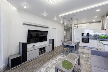 modern, bright living space featuring a kitchen, dining area, and living room. The decor is...