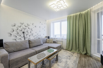 cozy living room features a gray sectional sofa, a nesting coffee table, and a large dandelion wall...