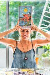Smiling tarot reader proudly displaying the giant Tarot card The Star high above