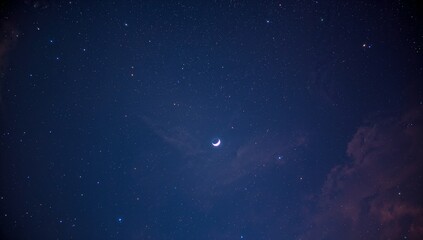 A crescent moon glows softly among countless stars within the deep night sky, featuring faint drifting clouds adding texture and depth to the tranquil celestial scene
