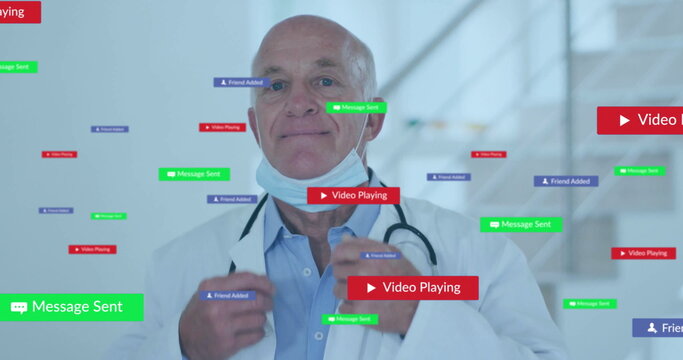 Adjusting senior male doctor pulling mask straps in clinic corridor, floating notifications - Powered by Adobe