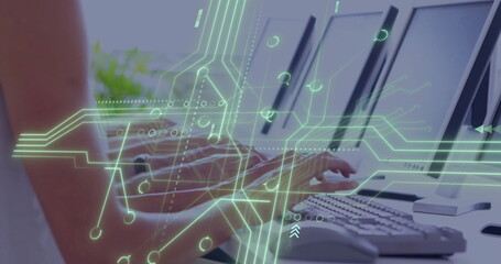Typing office professional using keyboard at desk with three monitors, circuit overlay