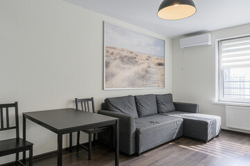 cozy living space with a grey sofa, dark table and chairs, and a beach-themed picture
