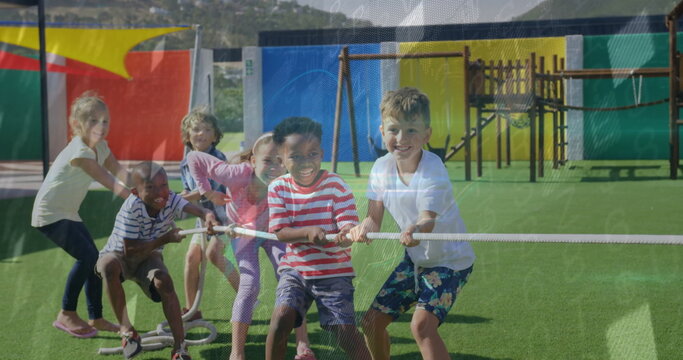 Pulling group of six children playing tug-of-war on synthetic turf field, with thick white rope