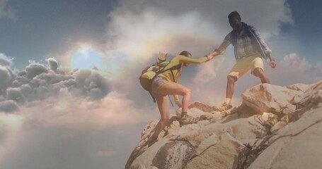 Climbing couple in hiking gear helping each other at mountain peak, with backpacks and water bottle