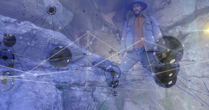 Adult explorer standing in narrow canyon wearing brim hat and jacket, with glowing network overlay - Powered by Adobe