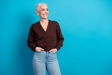 Charming mature woman in casual cardigan embraces positivity against a bright blue backdrop