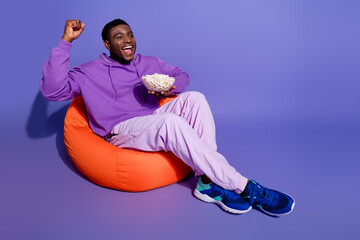 Young man enjoying leisure time on a vibrant background with snacks and a cheerful smile wearing...