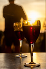 Two glasses of red wine on a table at sunset, with a shallow depth of field