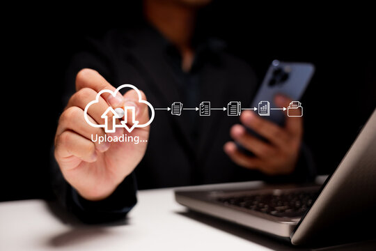 Cloud uploading and data transfer. A businessman uses a digital touchscreen and smartphone in a modern office to upload and sync files securely through cloud technology for business workflow.