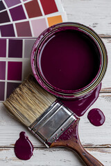 top view of plum paint can with brush and color palette on wooden background
