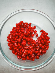 Fresh pomegranate seeds filling a glass bowl on a table