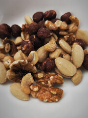 Mixed nuts filling a small white bowl, healthy snacking and autumn vibes