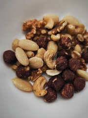 Mixed nuts filling a white bowl, healthy snack or ingredient for autumn recipes