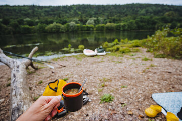 Enjoy a Serene Camping Experience alongside the River, complete with a Warm Mug of Coffee to enhance your time in nature. Embrace the peacefulness and tranquility while exploring the outdoors