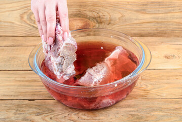 A woman's hand took meat out of a bowl of water.