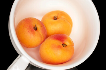 Ripe organic apricots isolated on black background, macro.