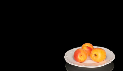 Ripe organic apricots isolated on black background, macro.