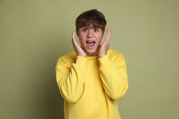 Teenage boy suffering from panic attack on green background