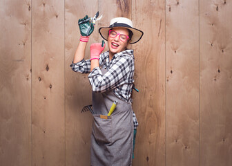 Party female farmer with closed eyes dancing on wooden background in studio. Playful young gardener...