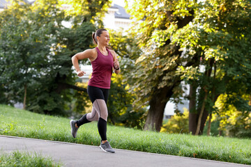 Athletic young woman in sportswear running outdoors, space for text