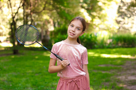 Portrait of smiling little girl with badminton racket in park