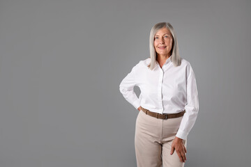Portrait of beautiful senior woman on grey background. Space for text