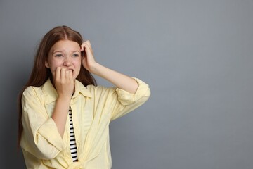 Teenage girl suffering from panic attack on grey background. Space for text