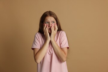 Teenage girl suffering from panic attack on beige background