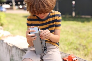 Little boy playing with toy car outdoors, selective focus