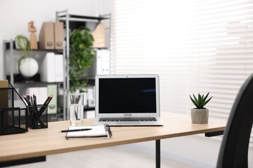 Stylish workplace with laptop and stationery on wooden table in office