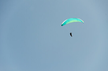 Paraglider flying high above the mountains with stunning panoramic views. Adventure and extreme sport.