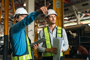 Engineers wearing safety helmets inspecting railway blueprint beside a vintage locomotive, symbolizing teamwork, innovation, and development in modern rail transportation and infrastructure projects