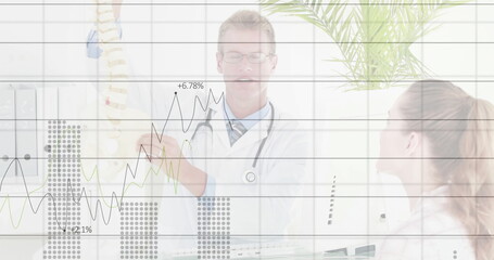 Pointing male physician explaining spine model to patient at clinic, with stethoscope