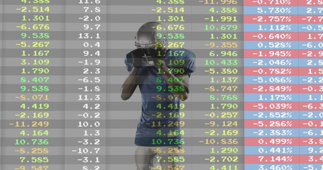 Gripping football helmet, gloved player in blue jersey standing against financial data backdrop