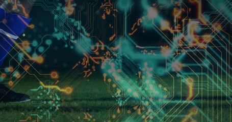 Soccer player leg showing blue sock, black cleat on turf with digital circuitry overlay, copy space