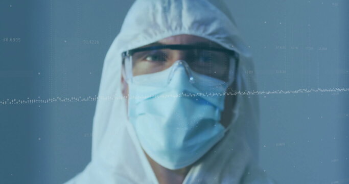 Standing male wearing coverall with hood, goggles and surgical mask in lab, with data graph overlay
