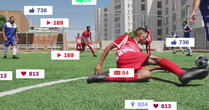 Sliding man in red uniform tackling opponent near soccer ball on pitch, with social media icons - Powered by Adobe