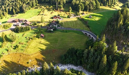 Drone shot of a scenic rural area in Switzerland mountains with a river and a bridge, near Nessental. 