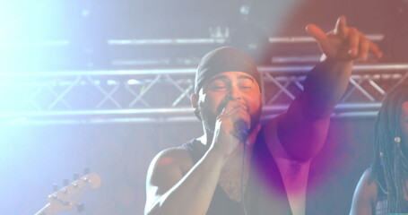 Gripping microphone, singer reaching out on stage under metal truss with lights and guitar neck