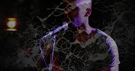 Singing performer wearing light shirt holding microphone stand under spotlight on stage, copy space